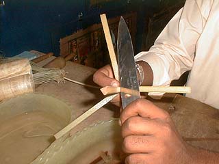 Removing the outer skin of the papyrus stem with a knife
